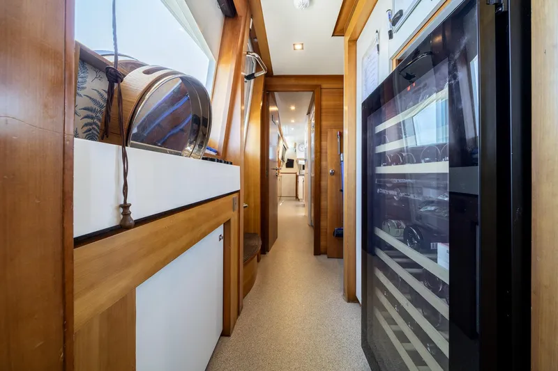 Arion Yacht Photos Pics Luxurious interior hallway of 2011 Guy Couach 121' yacht with wooden accents and wine cooler.