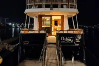 Luxury yacht "Floating Art" by De Groot, 1984 model, docked at night with illuminated interior.