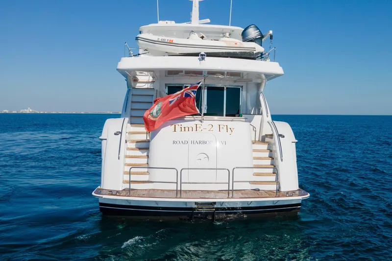 Time-2 Fly Yacht Photos Pics Hatteras 80 Motor Yacht Sky Lounge 2006 on open sea, rear view with flag.