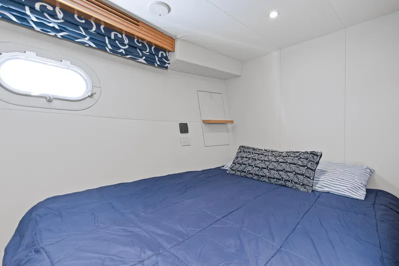 Time-2 Fly Yacht Photos Pics Cozy bedroom in 2006 Hatteras 80 Motor Yacht Sky Lounge with blue bedding and porthole window.