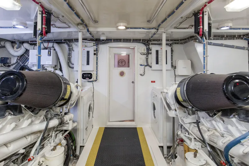 Time-2 Fly Yacht Photos Pics Engine room of 2006 Hatteras 80 Motor Yacht Sky Lounge, featuring dual engines and control panels.