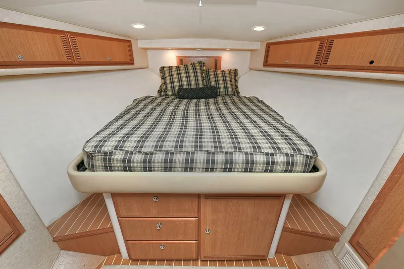 Trios Yacht Photos Pics 2007 Cabo 40 Express cabin interior with bed, wooden cabinets, and plaid bedding.