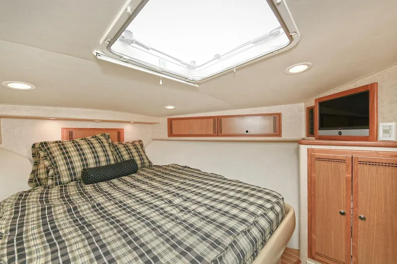Trios Yacht Photos Pics Luxurious cabin interior of 2007 Cabo 40 Express yacht, featuring a cozy bed and wooden cabinetry.