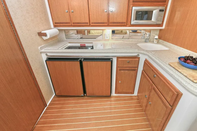 Trios Yacht Photos Pics 2007 Cabo 40 Express yacht kitchen with wooden cabinets, microwave, and countertop sink.
