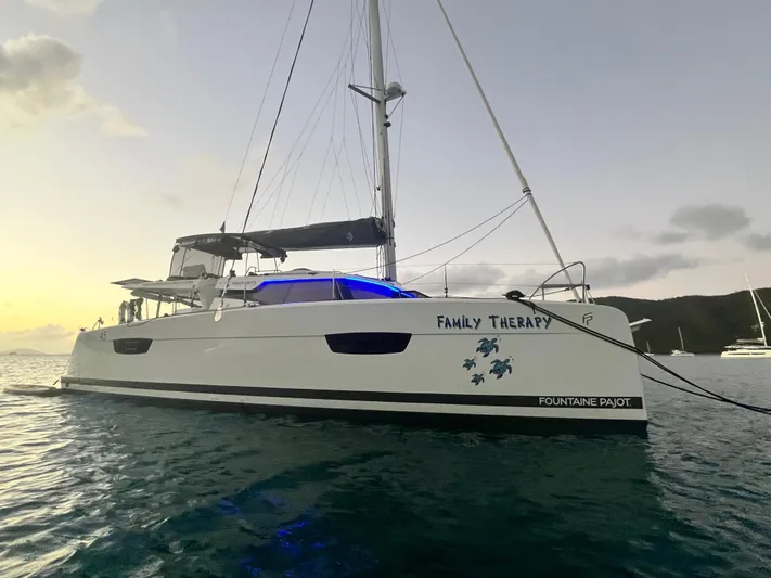 Family Therapy Yacht Photos Pics 2023 Fountaine Pajot Elba 45 catamaran named "Family Therapy" on tranquil water at sunset.
