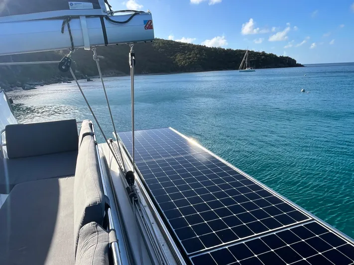 Family Therapy Yacht Photos Pics 2023 Fountaine Pajot Elba 45 catamaran with solar panels, anchored near a scenic beach.