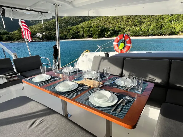 Family Therapy Yacht Photos Pics Luxurious dining setup on 2023 Fountaine Pajot Elba 45 yacht, overlooking serene beach.