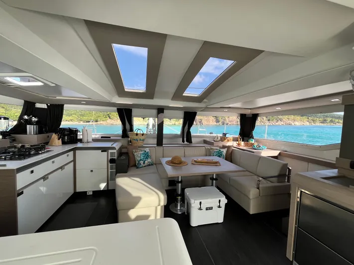 Family Therapy Yacht Photos Pics Luxurious interior of 2023 Fountaine Pajot Elba 45 catamaran with panoramic windows and modern furnishings.