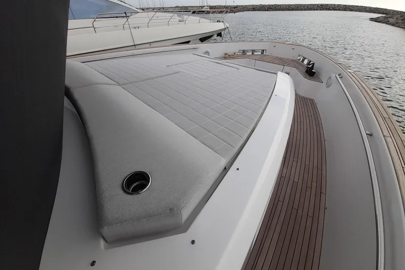  Yacht Photos Pics 2023 Pardo Yachts E60 deck with cushioned seating and wooden flooring, docked by the water.