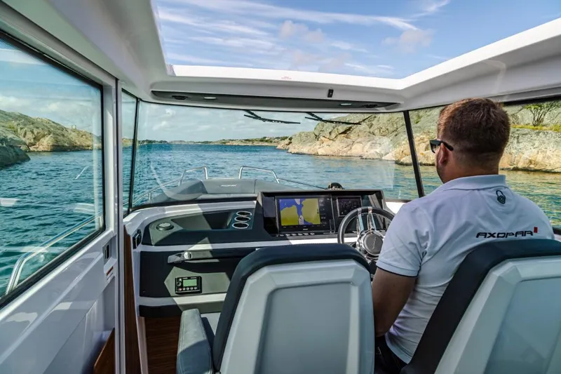 Yacht Photos Pics Man steering Axopar 28 CABIN boat on calm waters.