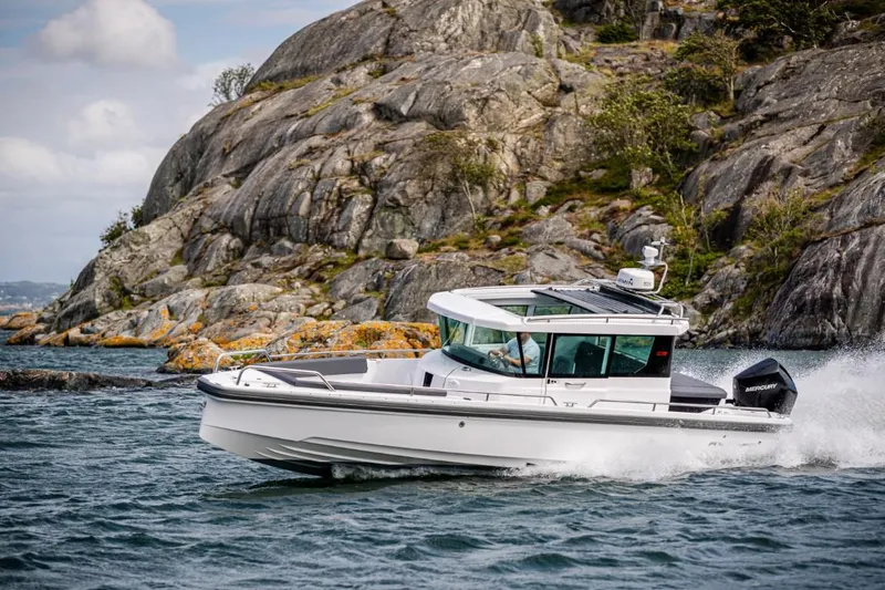  Yacht Photos Pics Axopar 28 CABIN 2022 cruising near rocky coastline.