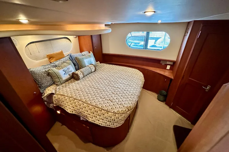  Yacht Photos Pics Luxurious bedroom in 2005 Silverton 43 Motor Yacht with cozy bedding and elegant wood finishes.