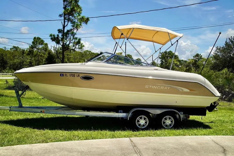  Yacht Photos Pics 2001 Stingray 240 LS boat on trailer with canopy, parked on grass.