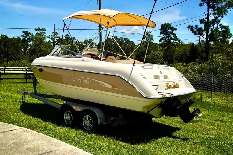  Yacht Photos Pics 2001 Stingray 240 LS boat on trailer with canopy, parked on grass.