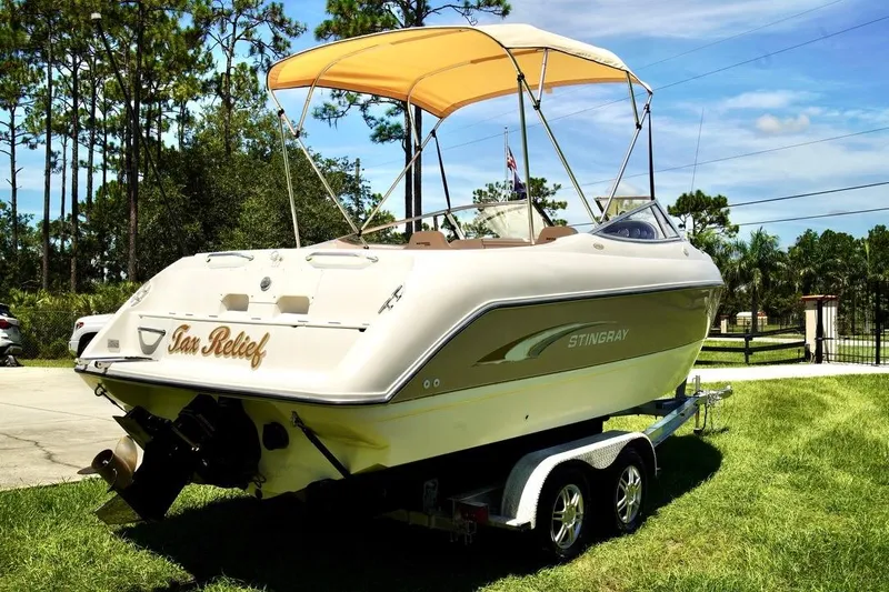  Yacht Photos Pics 2001 Stingray 240 LS boat on trailer with canopy, parked on grass.