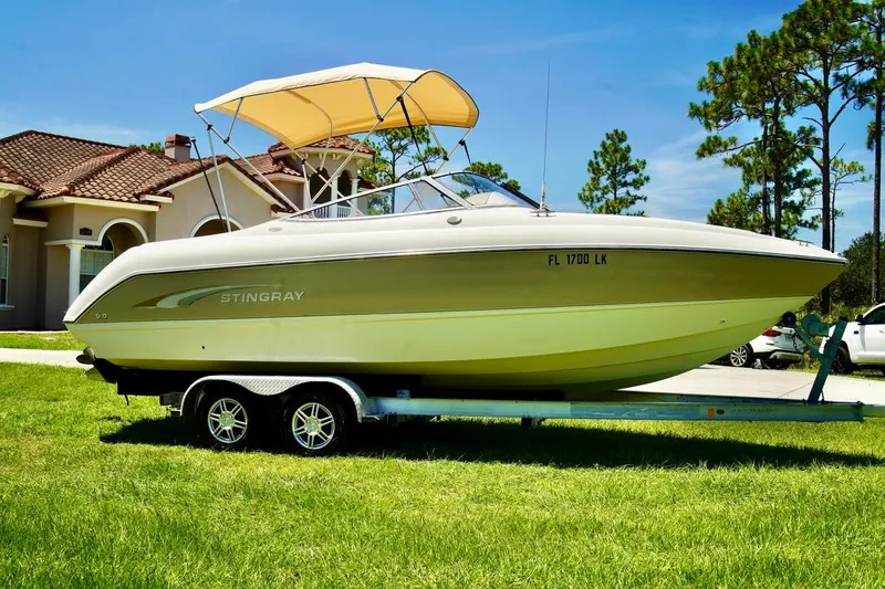 Yacht Photos Pics 2001 Stingray 240 LS boat on trailer, parked on grass near a house.