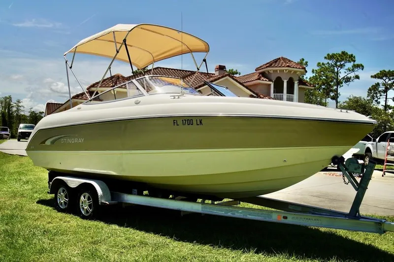  Yacht Photos Pics 2001 Stingray 240 LS boat on trailer, parked near a house with a canopy.