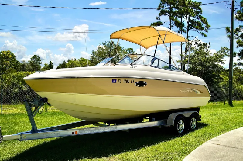  Yacht Photos Pics 2001 Stingray 240 LS boat on trailer with canopy, parked on grass under blue sky.
