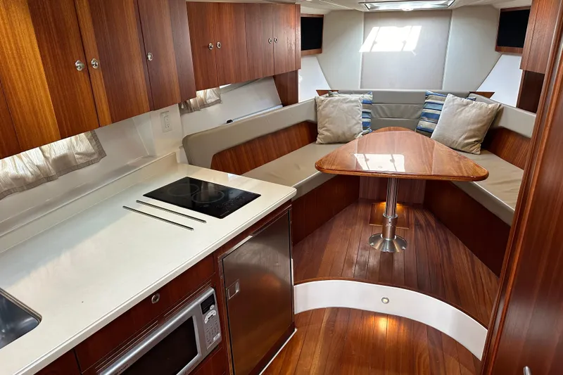 Yolo Or 2 Yacht Photos Pics 2014 Pursuit SC 365i Sport Coupe interior with wood cabinetry, kitchenette, and cozy seating area.