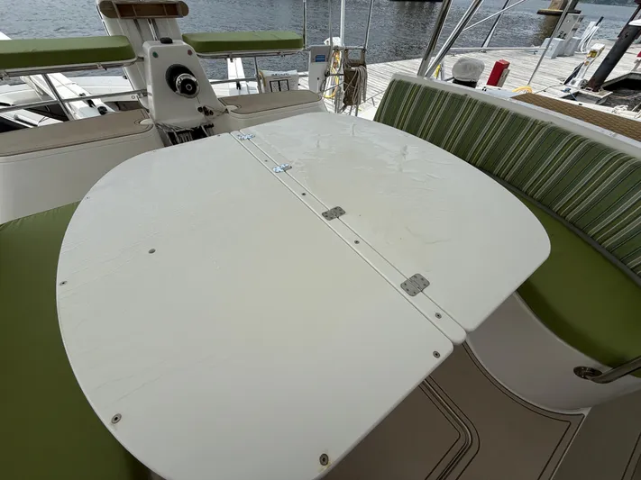 Two Fish Yacht Photos Pics Antares 44GS 2021 yacht cockpit with foldable table and green cushioned seating.
