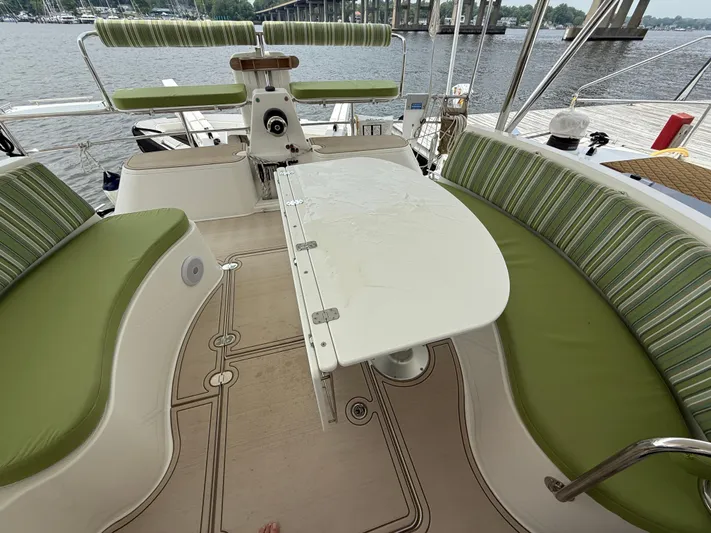 Two Fish Yacht Photos Pics Antares 44GS 2021 yacht cockpit with green seating and white table, overlooking water.