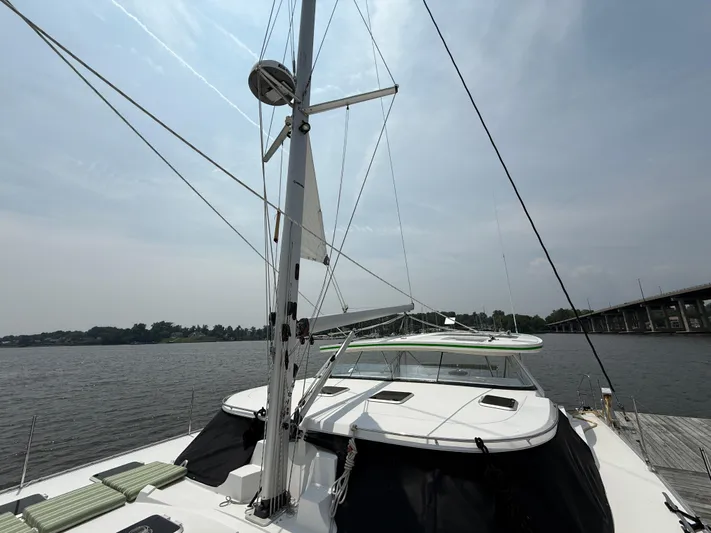 Two Fish Yacht Photos Pics Sailing yacht Antares 44GS, 2021 model, docked by a calm river under a cloudy sky.
