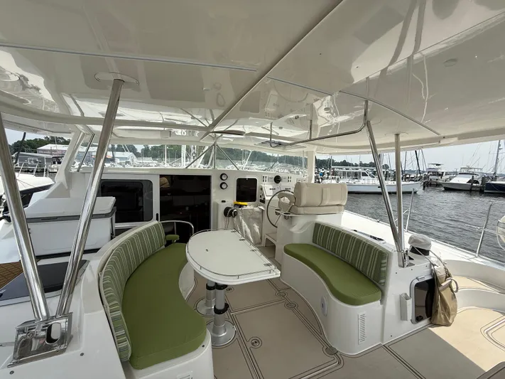 Two Fish Yacht Photos Pics 2021 Antares 44GS yacht cockpit with green seating, table, and helm, docked at marina.