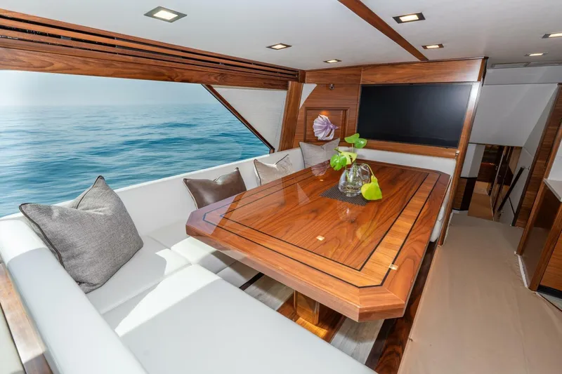 Zatara Yacht Photos Pics Luxurious interior of 2025 Viking 90 Convertible yacht with elegant wood dining table and ocean view.