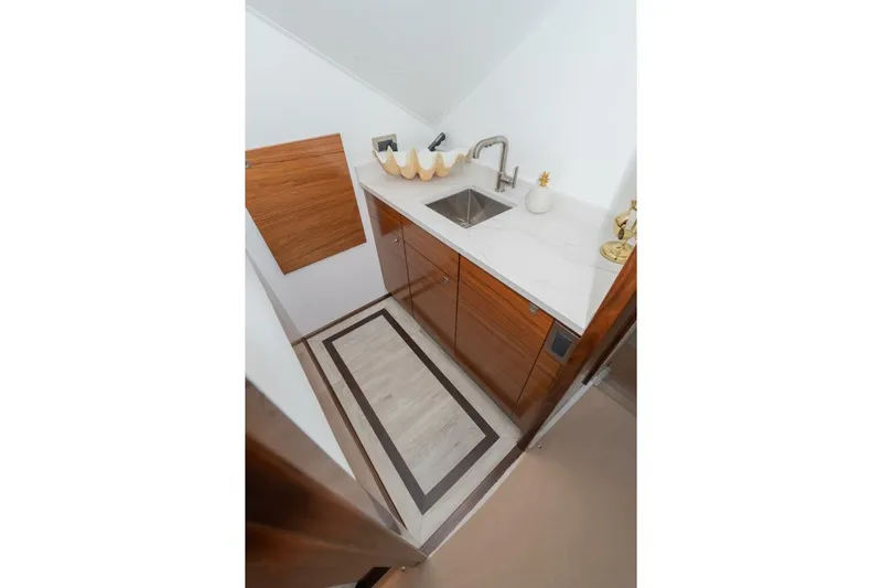 Zatara Yacht Photos Pics Compact kitchen area in 2025 Viking 90 Convertible yacht with modern sink and wooden cabinetry.