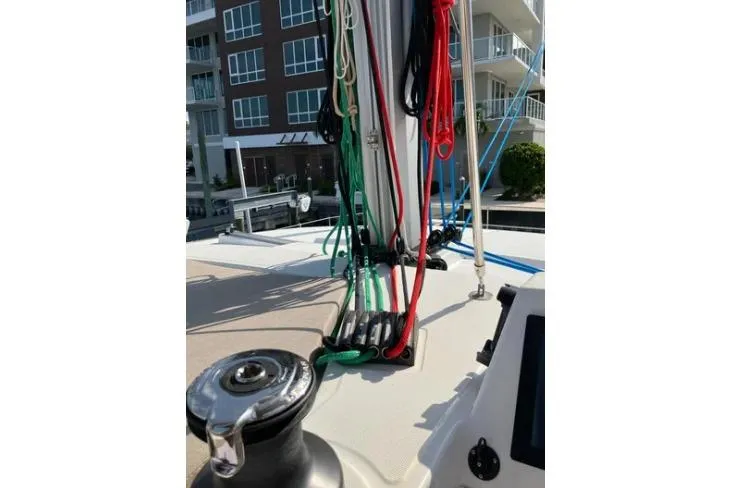 Nauti Habit Yacht Photos Pics 2023 Bali 4.2 sailboat deck with colorful ropes and winch near modern buildings.