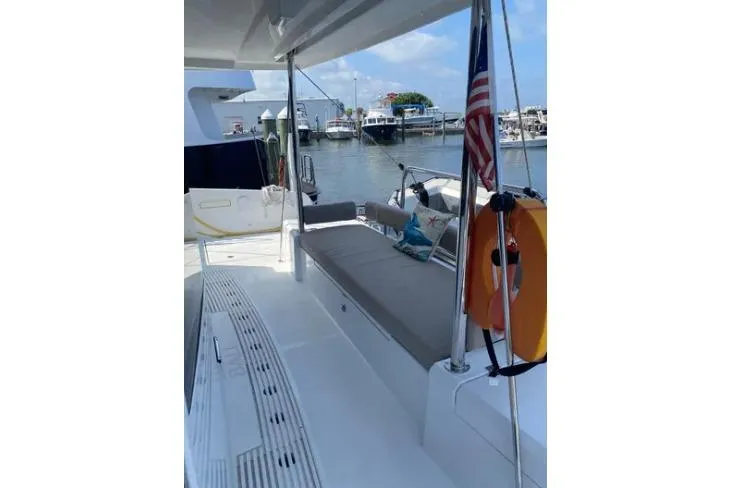 Nauti Habit Yacht Photos Pics 2023 Bali 4.2 yacht deck with seating, docked at marina, American flag displayed.
