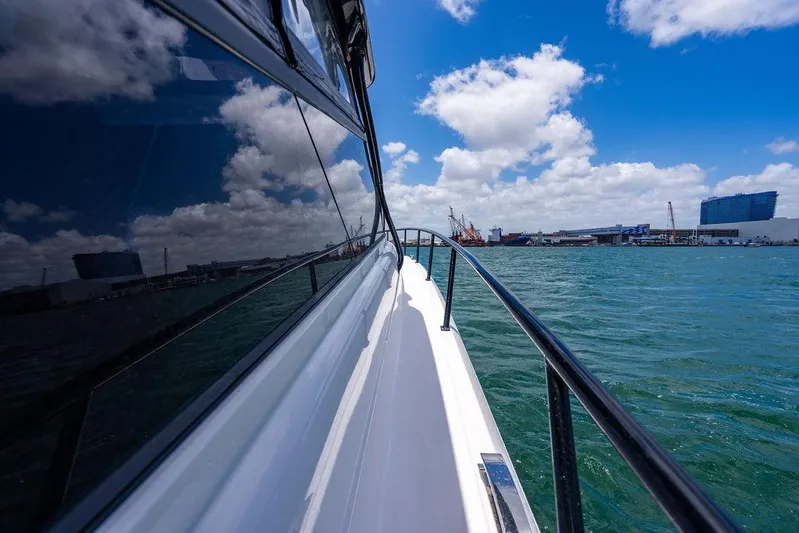  Yacht Photos Pics Side view of 2021 Intrepid 477 Evolution yacht on water, reflecting blue sky and clouds.