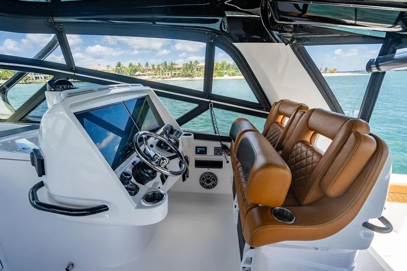  Yacht Photos Pics 2021 Intrepid 477 Evolution helm with leather seats and modern controls, overlooking serene waters.