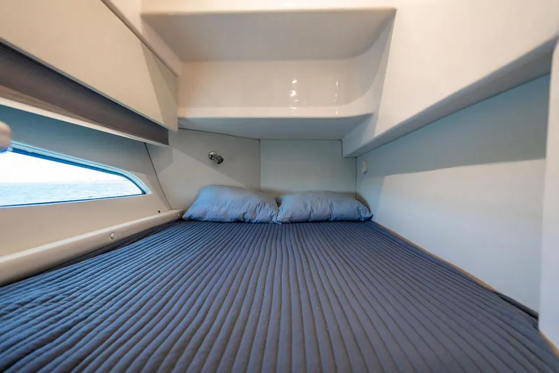  Yacht Photos Pics Cozy cabin bed in 2021 Intrepid 477 Evolution yacht with blue bedding and window view.