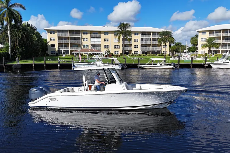  Yacht Photos Pics 2022 Pursuit S 288 Sport boat cruising on a sunny day near waterfront buildings.