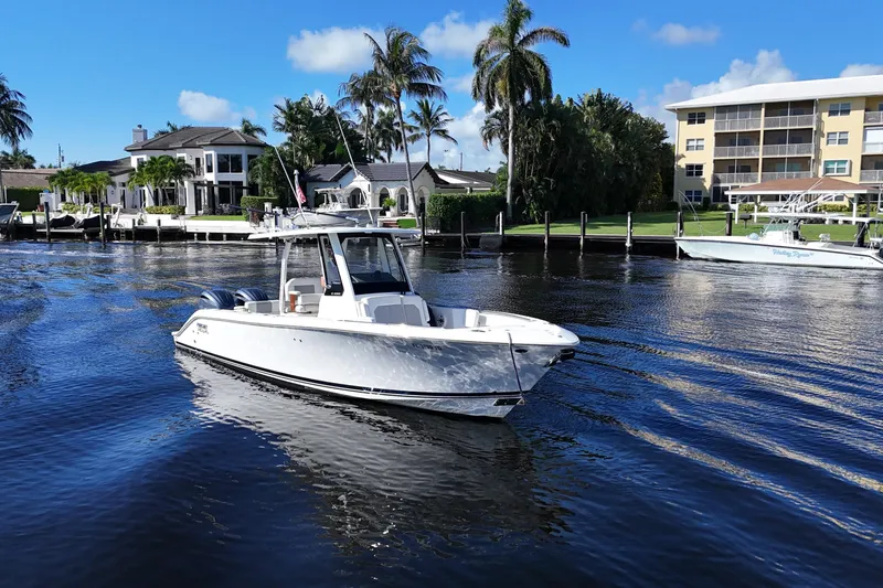  Yacht Photos Pics 2022 Pursuit S 288 Sport boat cruising near waterfront homes and palm trees.