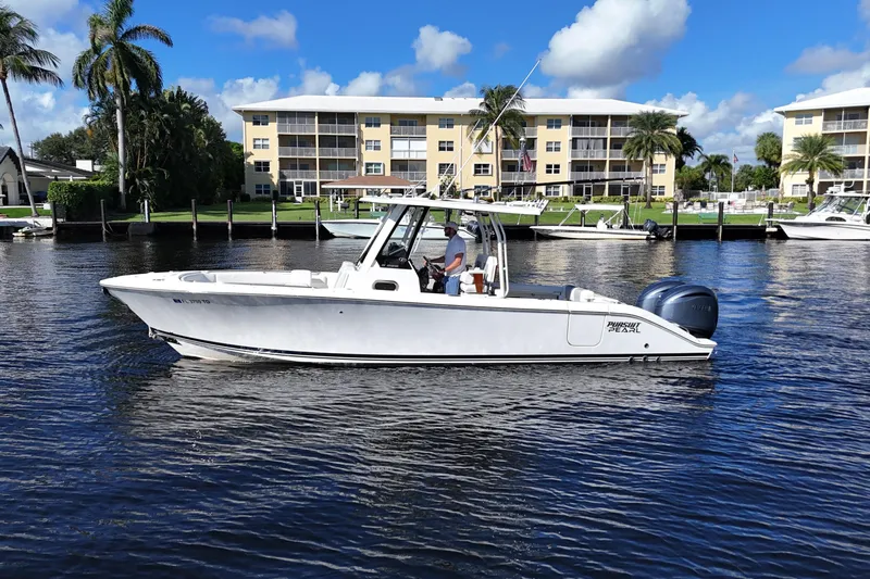  Yacht Photos Pics 2022 Pursuit S 288 Sport boat cruising on a sunny day near waterfront buildings.
