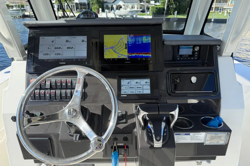  Yacht Photos Pics Control panel of 2022 Pursuit S 288 Sport boat with navigation screens and steering wheel.
