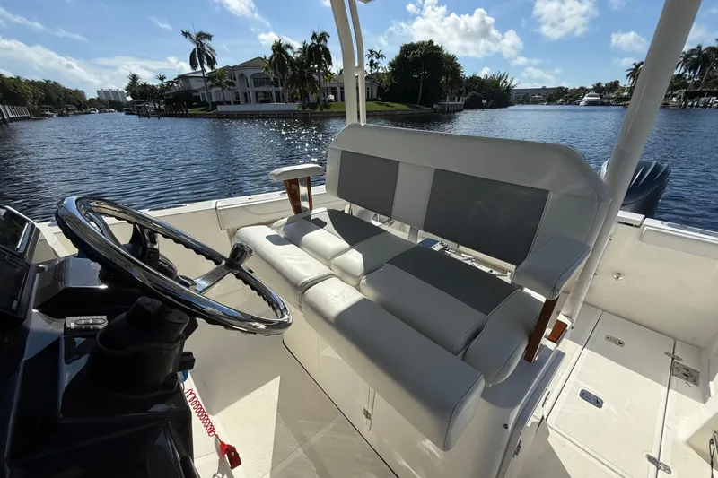  Yacht Photos Pics 2022 Pursuit S 288 Sport boat interior with steering wheel and seating, on a sunny waterfront.