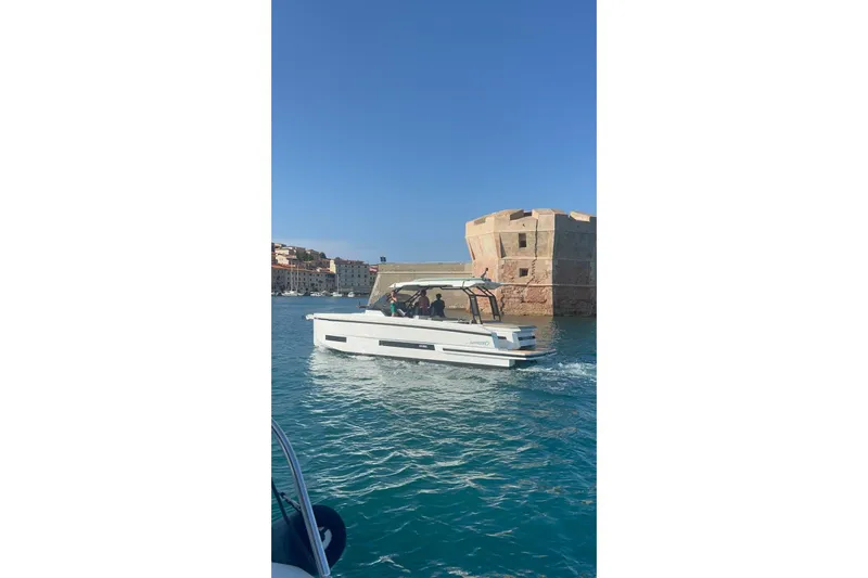  Yacht Photos Pics 2024 DE ANTONIO D32 boat cruising near historic coastal fort.