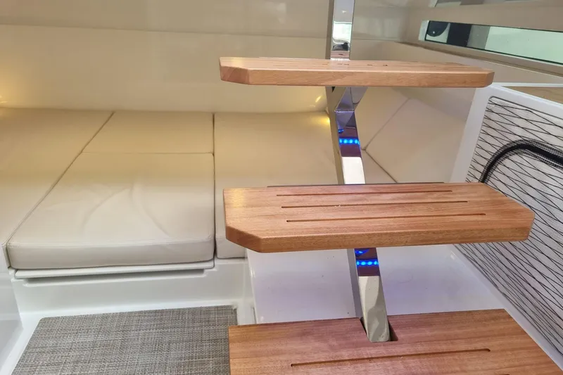  Yacht Photos Pics 2024 DE ANTONIO D32 interior with wooden steps and cushioned seating.