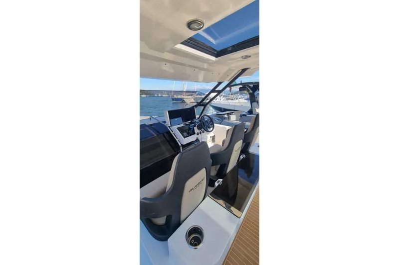  Yacht Photos Pics 2024 De Antonio Yachts D32 cockpit with modern controls and seating, docked by the sea.