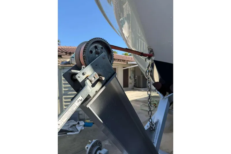  Yacht Photos Pics 2022 Contender 35 ST boat trailer winch and chain mechanism in a driveway setting.