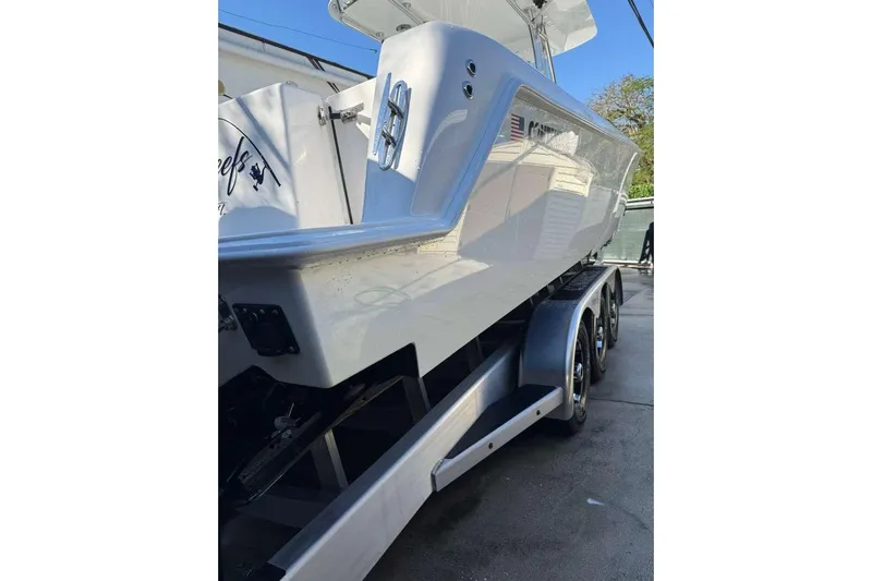 Yacht Photos Pics 2022 Contender 35 ST boat on trailer, side view, showcasing sleek design and triple-axle support.