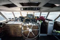Interior of a 1991 custom boat cockpit with navigation equipment and wooden steering wheel.