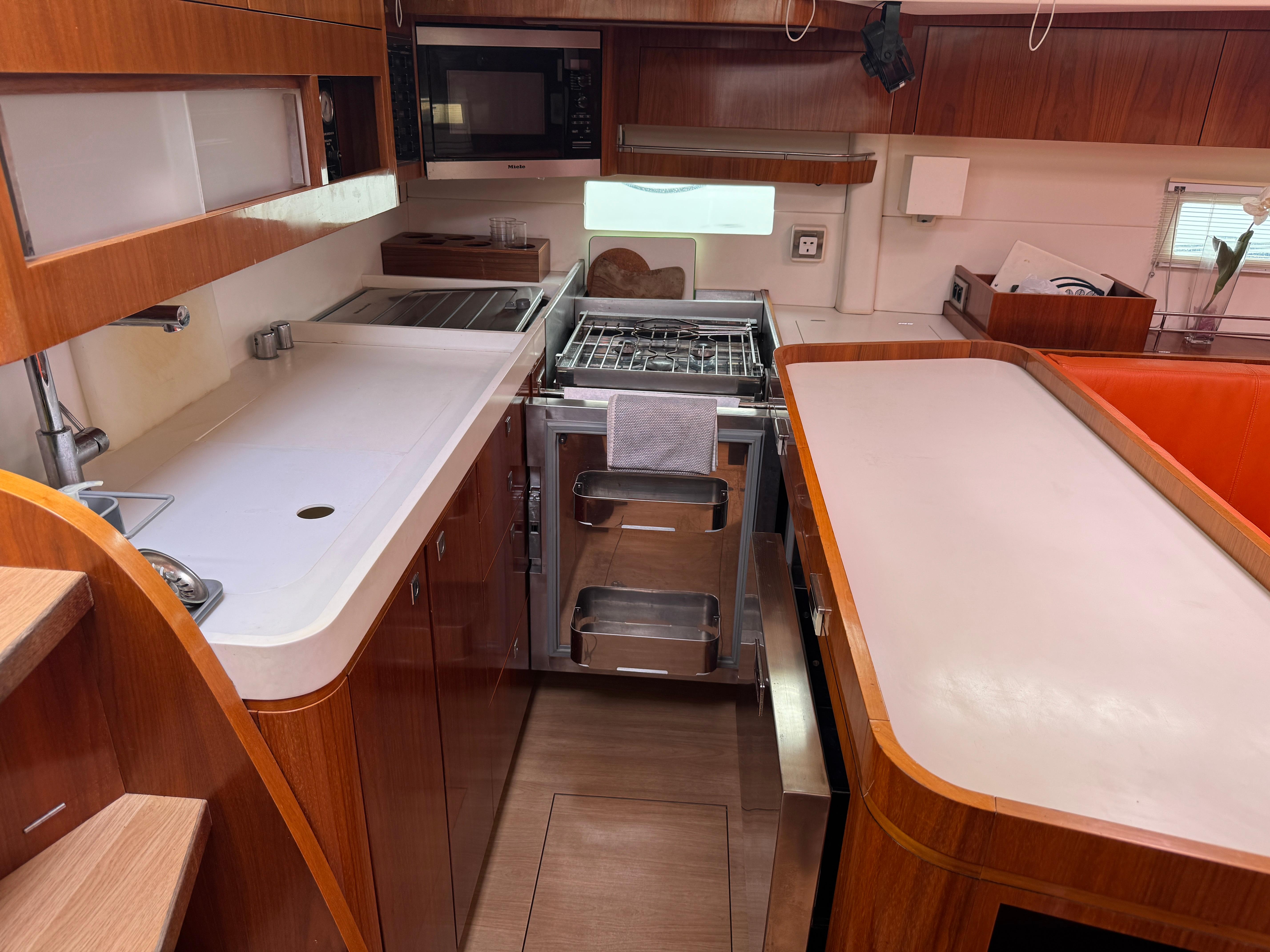 Modern kitchen interior of 2012 Amel 55 yacht with wooden cabinetry and stainless steel appliances.
