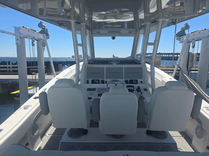  Yacht Photos Pics 2024 Invincible 43 Open Fisherman boat interior with helm and seating, docked by the water.