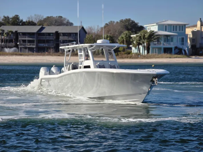  Yacht Photos Pics 2024 Invincible 43 Open Fisherman boat cruising near a coastal shoreline.