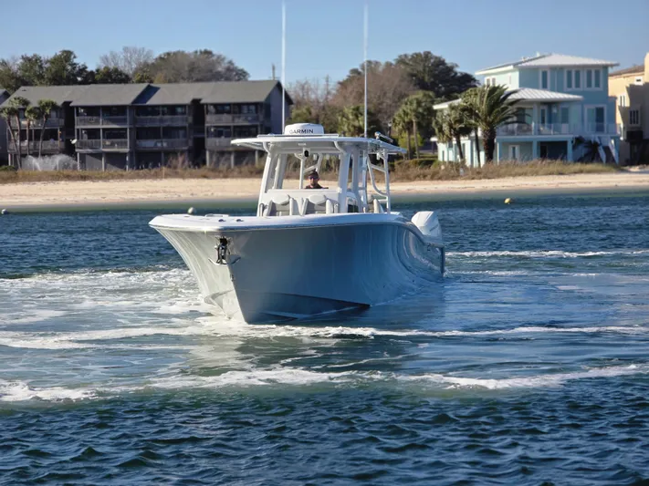  Yacht Photos Pics 2024 Invincible 43 Open Fisherman boat cruising near a sandy shoreline.