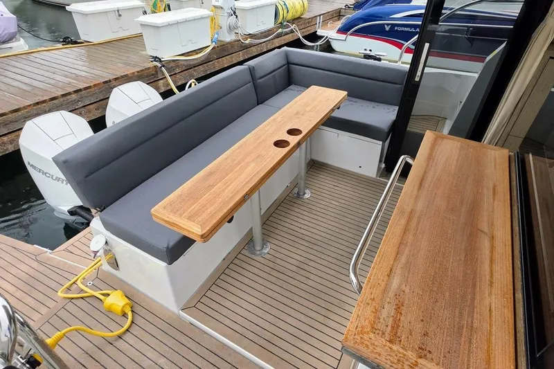  Yacht Photos Pics 2023 Sealine C335V boat deck with wooden table and cushioned seating.
